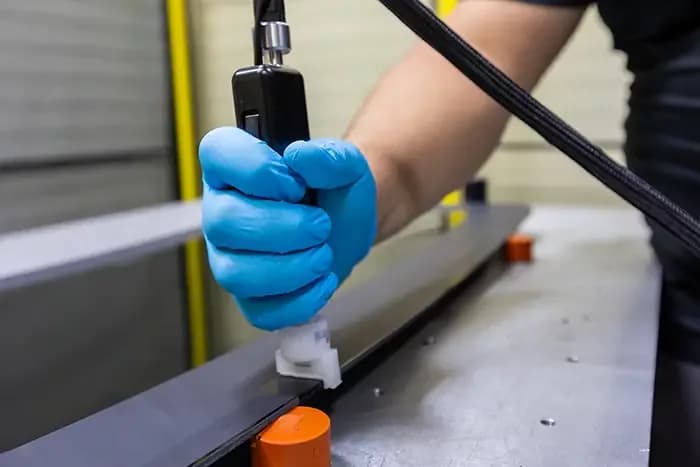 technician using a flat fluid applicator on a glass product.