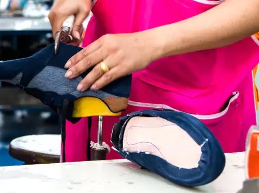 Woman working on assembling a shoe.